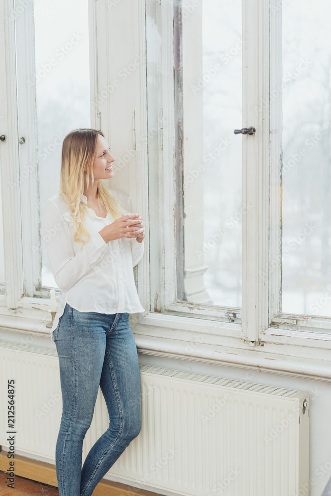 Slender woman in jeans staring out of a window