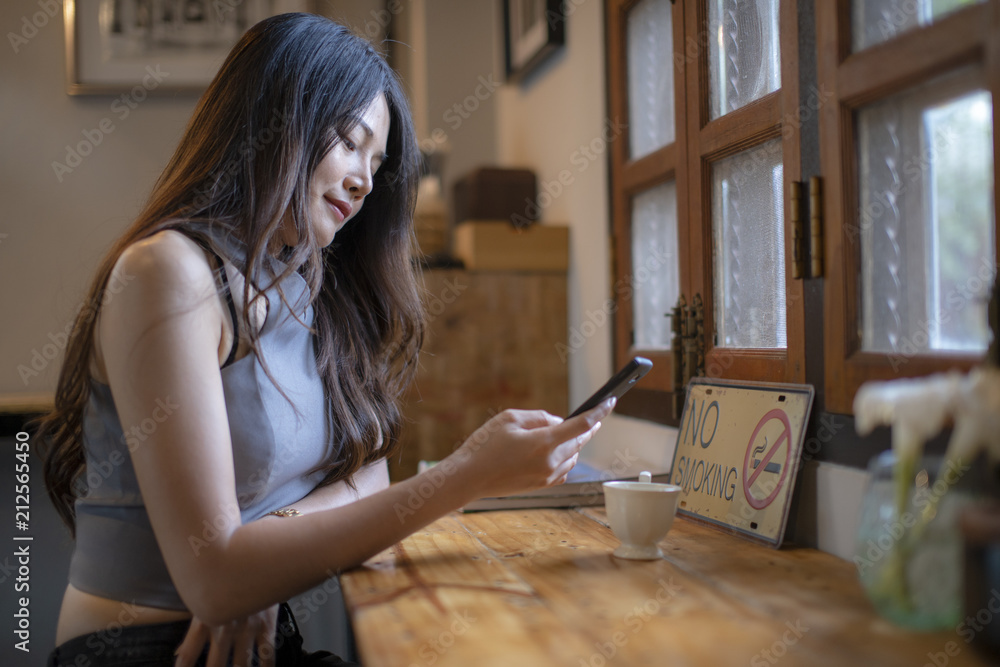 Asian women check cell phone information in coffee shop Asian women check cell phone information in coffee shop