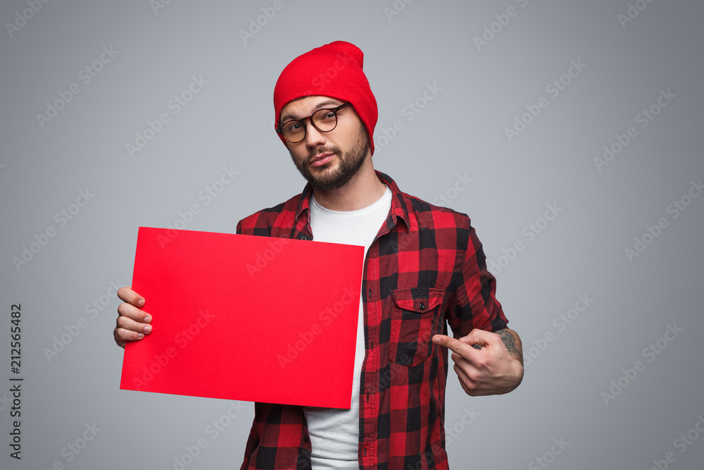 Young man pointing at red poster Young man pointing at red poster