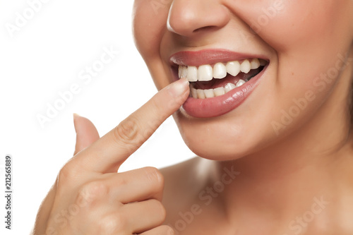 young woman touchng her teeth with her finger on white background photo