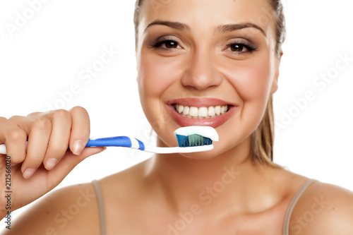 young smiling woman holding a toothbrush on white background