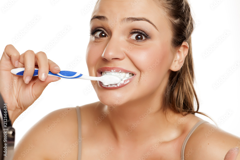 young happy woman brushing her teeth on white background young happy woman brushing her teeth on white background