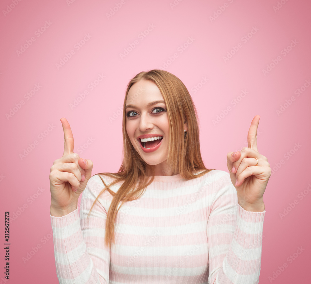 Excited attractive young female pointing up Excited attractive young female pointing up