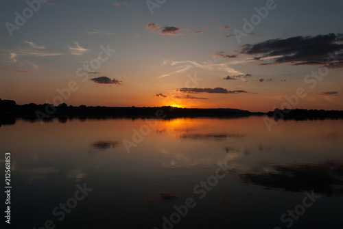  beautiful colorful summer sunrise on the Dnipro river in Tobeltsi village, Cherkaska oblast, Ukraine. A sun rises over the water and colors the sky.  photo