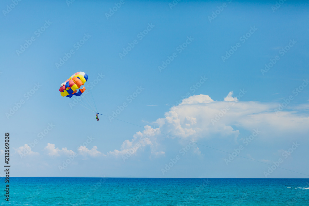 Couple of tourists flying on a colorful parachute Couple of tourists flying on a colorful parachute