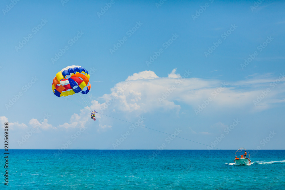 People flying on a colorful parachute towed by a motor boat People flying on a colorful parachute towed by a motor boat
