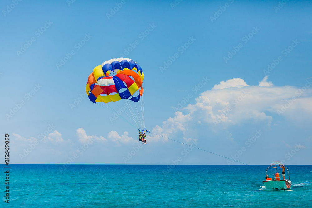 People flying on a colorful parachute towed by a motor boat