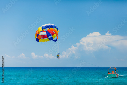 Obraz na płótnie People flying on a colorful parachute towed by a motor boat w salonie