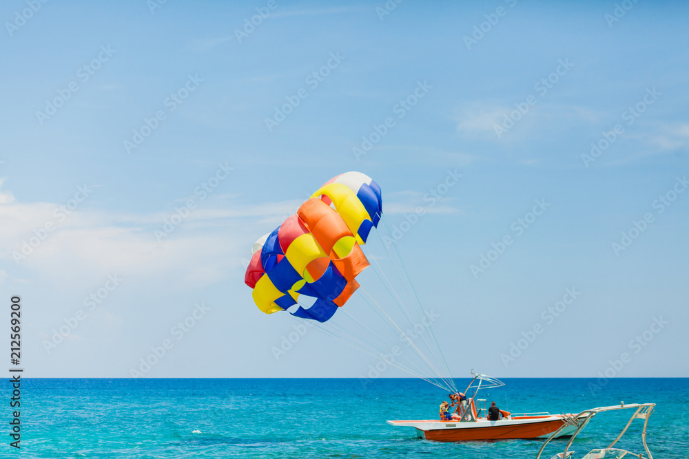 Couple of tourists flying on a colorful parachute Couple of tourists flying on a colorful parachute