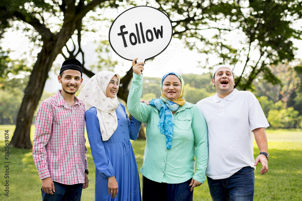 Muslim family holding up a follow sign Muslim family holding up a follow sign