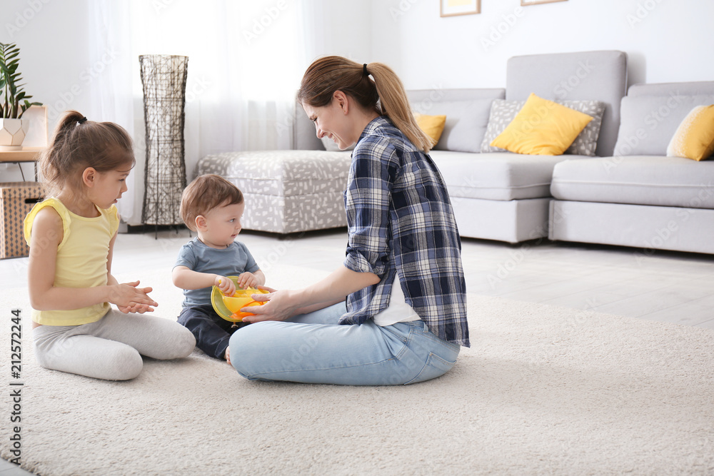 Mother with cute little children sitting on cozy carpet at home Mother with cute little children sitting on cozy carpet at home