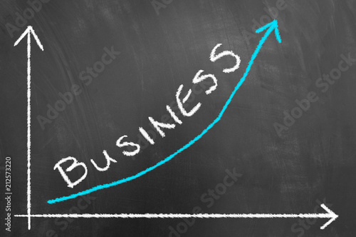 Business growing chart with arrow on blackboard or chalkboard.