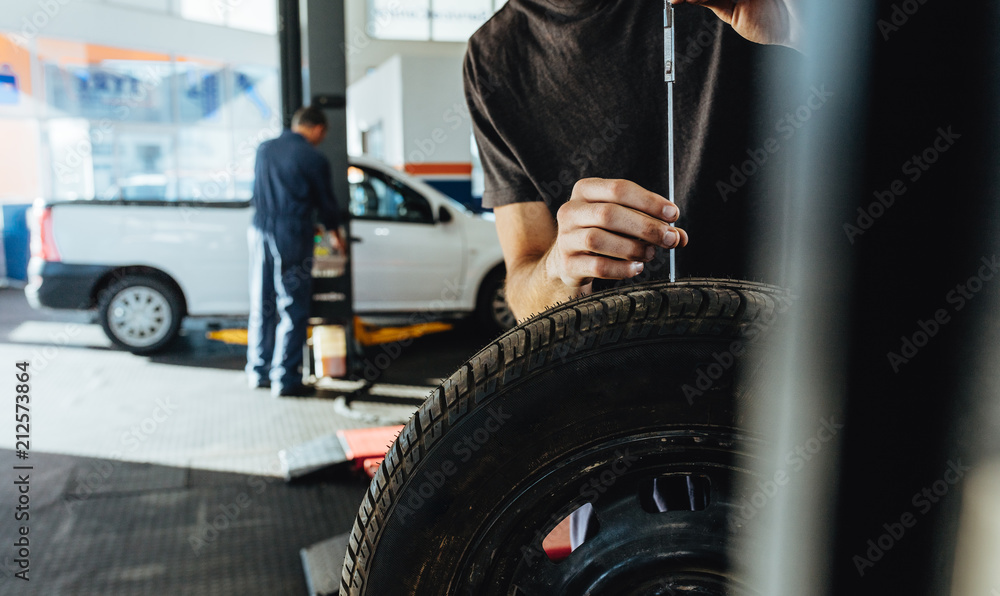 Mechanic checking car tire tread depth Mechanic checking car tire tread depth