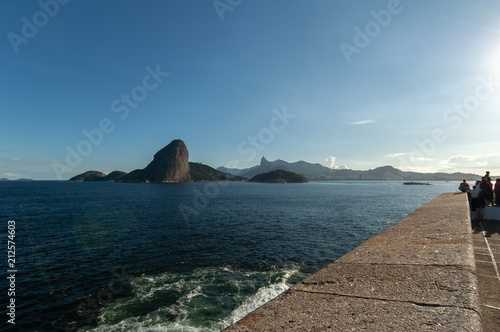 Sugar Loaf, Rio de Janeiro, tourist attraction, back view, a Brazil symbol. Sea, blue sky, boats and stone Pao de Acucar, seen from Niteroi city, located across the Guanabara Bay. photo