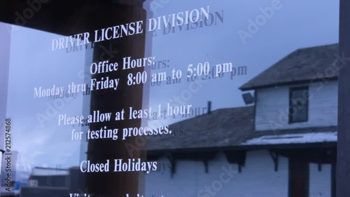 Drivers license division and hours of operation white vinyl lettering on a glass door. photo