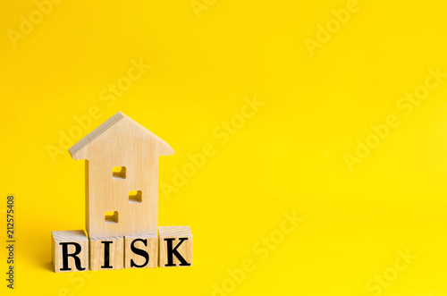 wooden house and cubes with the word "risk". Risk management concept. Real Estate. Property investment and house mortgage financial. yellow background. place for text. copy space