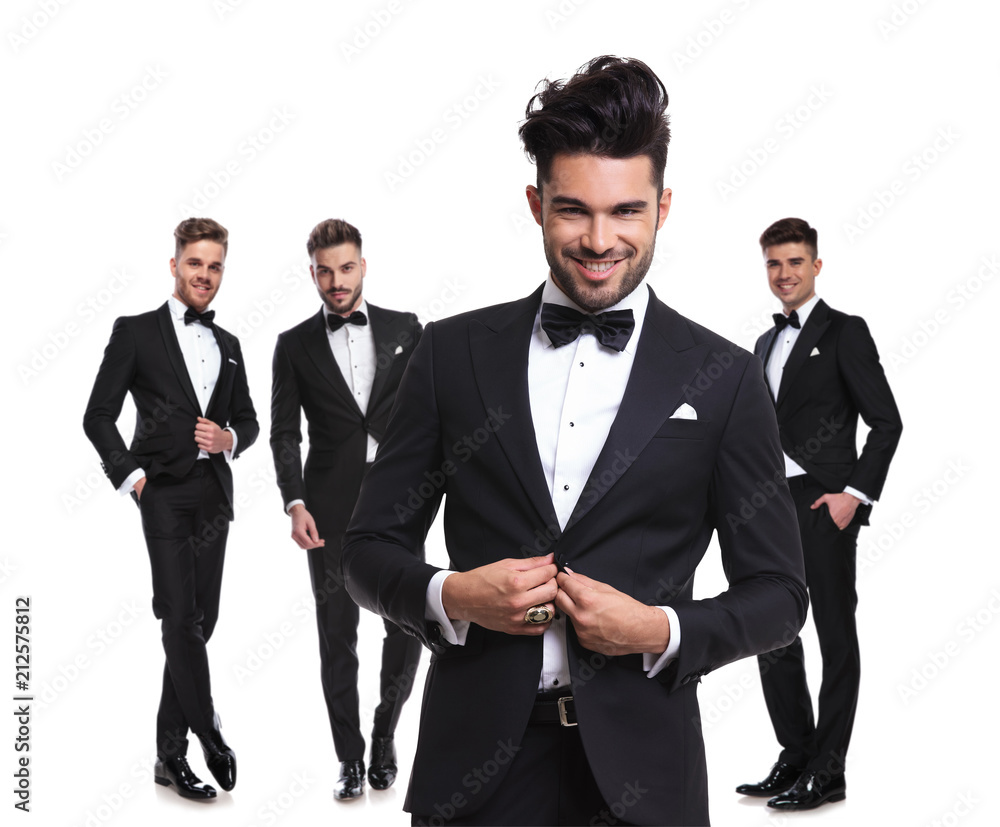 four elegant man with leader buttoning his tux in front four elegant man with leader buttoning his tux in front