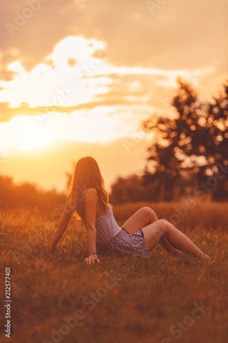 Girl enjoying in the meadow at golden sunset time.