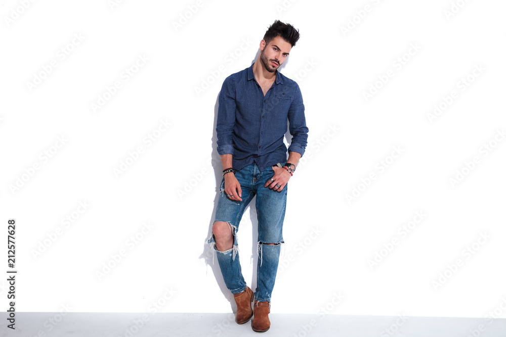 Naklejka premium sexy man in navy shirt leaning against a white wall