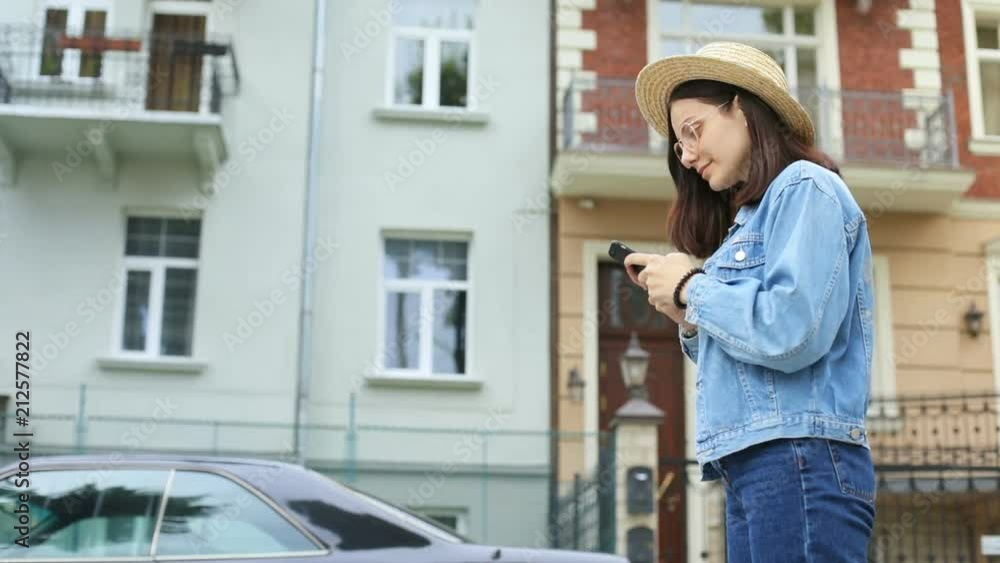 cute stylish woman in elegant straw hat and jeans jacket using smartphone while standing in front of beautiful modern building social networking online beauty blogger checking website attendance cute stylish woman in elegant straw hat and jeans jacket using smartphone while standing in front of beautiful modern building social networking online beauty blogger checking website attendance