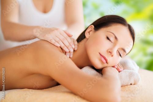 wellness, spa and beauty concept - close up of beautiful woman having massage over green natural background