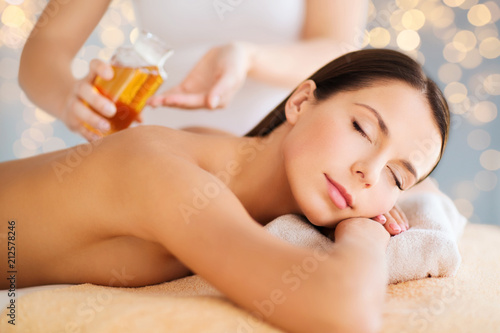 wellness, spa and beauty concept - close up of beautiful woman having massage over holidays lights background