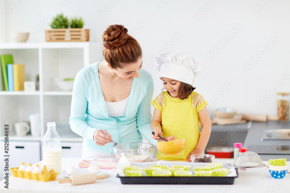 family, cooking, baking and people concept - happy mother and little daughter making batter for muffins at home kitchen family, cooking, baking and people concept - happy mother and little daughter making batter for muffins at home kitchen