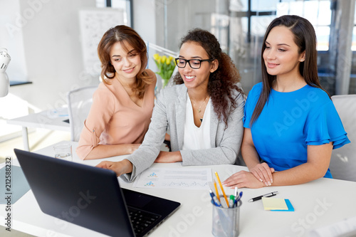 business, teamwork and people concept - female team or businesswomen with laptop computer working at office