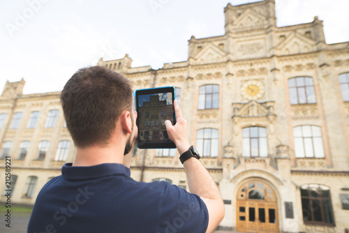 Man makes a picture of the old beautiful architecture on a tablet. Man photographs the building on the tablet.