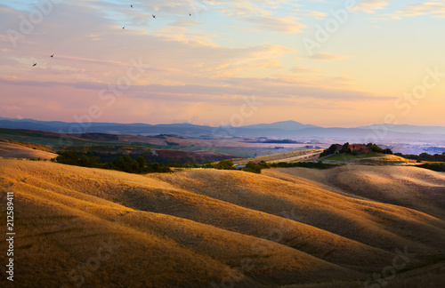 typical Tuscany landscape; sunset over rolling hills and Tuscany village