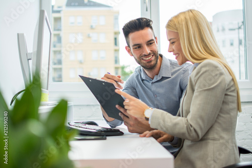 Businessman and business woman with clipboard discussing business project on meeting in office