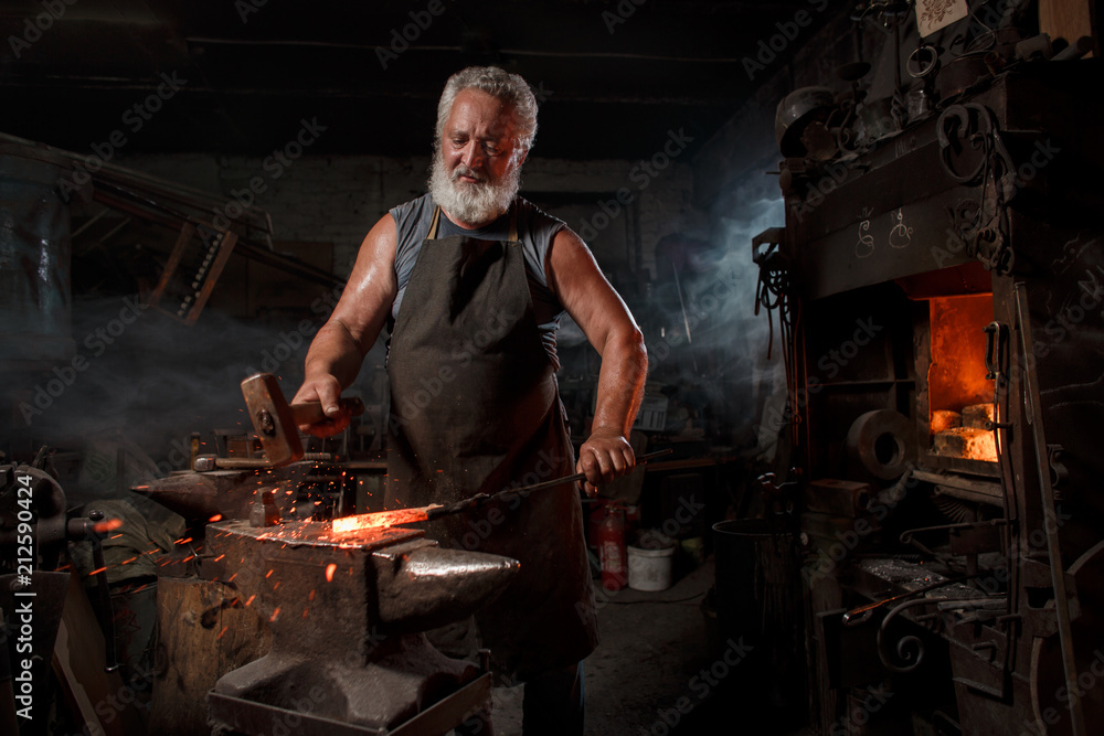 Blacksmith with brush handles the molten metal Blacksmith with brush handles the molten metal