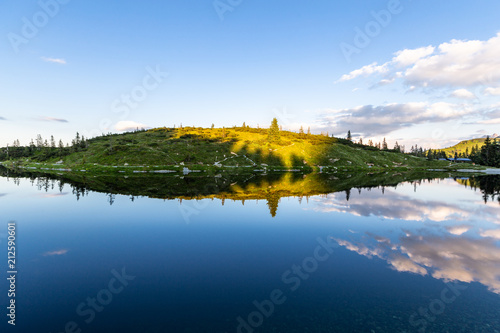 See spiegelt Landschaft im Sommer am Berg beim Sonnenuntergang