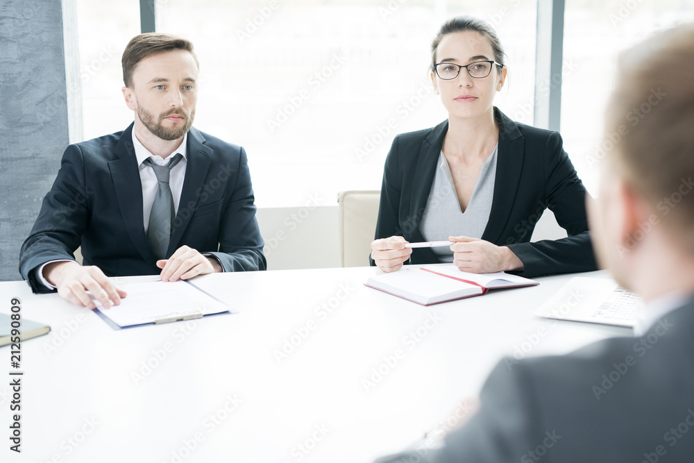 Portrait of two successful business people, man and woman, talking to partner sitting across meeting table and negotiating in conference room, copy space Portrait of two successful business people, man and woman, talking to partner sitting across meeting table and negotiating in conference room, copy space