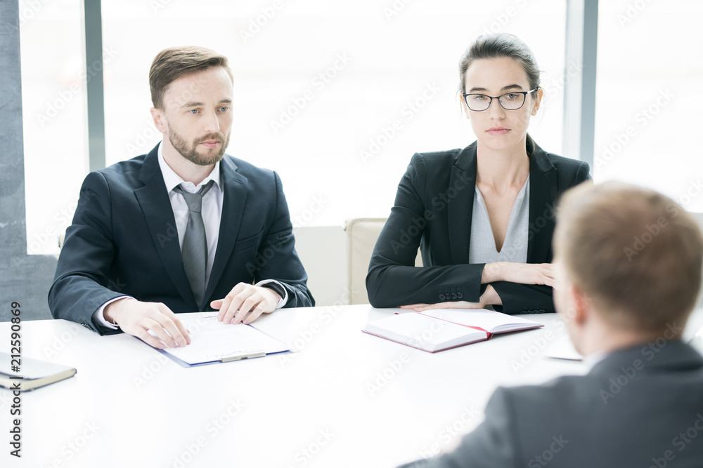 Portrait of two business people, man and woman, talking to partner sitting across meeting table in conference room, copy space Portrait of two business people, man and woman, talking to partner sitting across meeting table in conference room, copy space