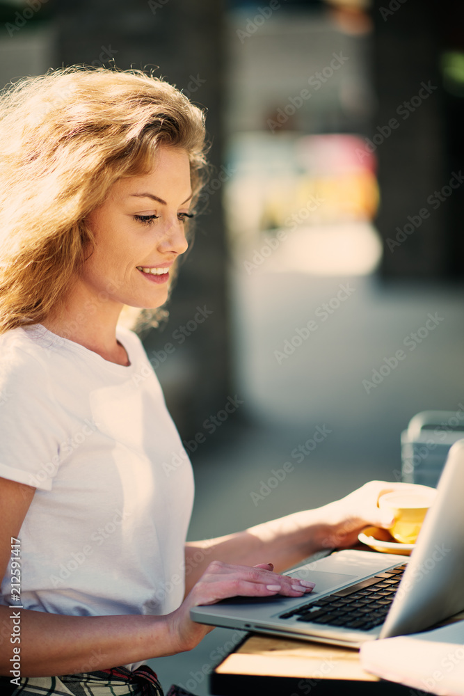 Female student drinking coffee and using laptop while sitting in cafe. Female student drinking coffee and using laptop while sitting in cafe.