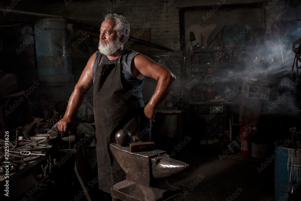 Portrait of a brutal blacksmith artisan in an apron in a blacksmith Portrait of a brutal blacksmith artisan in an apron in a blacksmith