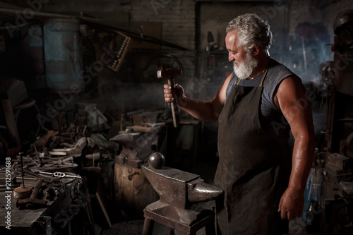 Portrait of a blacksmith artisan with a hammer in a blacksmith