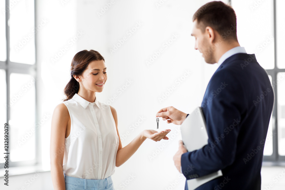 real estate business, sale and people concept - male realtor giving key to female customer or new office owner real estate business, sale and people concept - male realtor giving key to female customer or new office owner