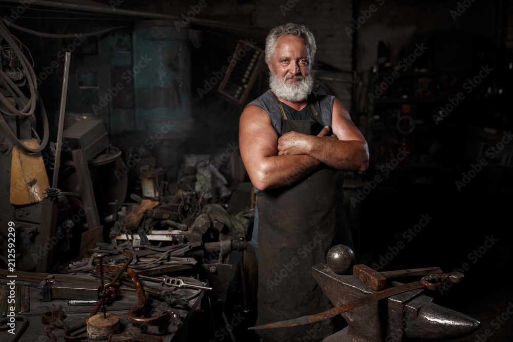 The portrait of blacksmith preparing to work metal on the anvil The portrait of blacksmith preparing to work metal on the anvil