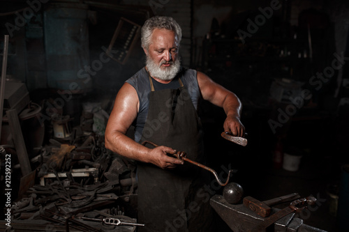 The portrait of blacksmith preparing to work metal on the anvil