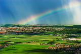Colorful rainbow over the green fields and vineyards