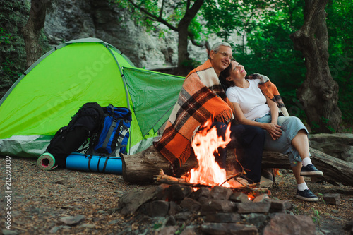 Tent camping couple romantic sitting by bonfire night countryside