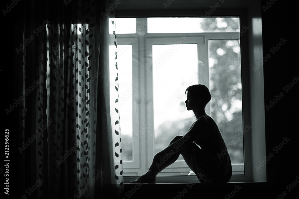 Silhouette of a dreamy girl sitting on a window Silhouette of a dreamy girl sitting on a window
