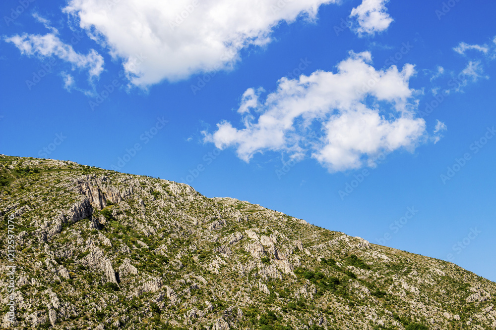 Blue sky and fluffy white clouds over the karst ridge of Chepan Mountain at Dragoman Marsh in Sofia Province, Bulgaria Blue sky and fluffy white clouds over the karst ridge of Chepan Mountain at Dragoman Marsh in Sofia Province, Bulgaria