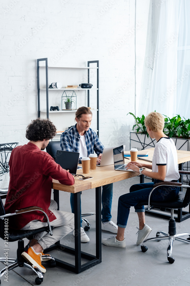 Obraz premium young business team using laptops while sitting together at workplace
