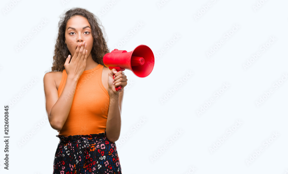 Young hispanic woman holding megaphone cover mouth with hand shocked with shame for mistake, expression of fear, scared in silence, secret concept Young hispanic woman holding megaphone cover mouth with hand shocked with shame for mistake, expression of fear, scared in silence, secret concept