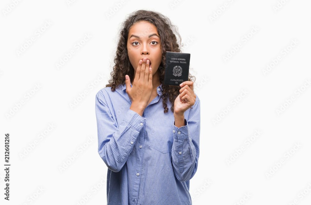 Young hispanic woman holding passport of Italy cover mouth with hand shocked with shame for mistake, expression of fear, scared in silence, secret concept Young hispanic woman holding passport of Italy cover mouth with hand shocked with shame for mistake, expression of fear, scared in silence, secret concept