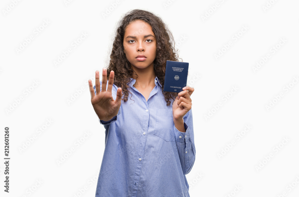Young hispanic woman holding passport of Germany with open hand doing stop sign with serious and confident expression, defense gesture Young hispanic woman holding passport of Germany with open hand doing stop sign with serious and confident expression, defense gesture