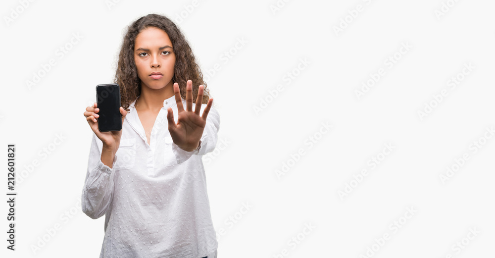Young hispanic woman using smartphone with open hand doing stop sign with serious and confident expression, defense gesture Young hispanic woman using smartphone with open hand doing stop sign with serious and confident expression, defense gesture
